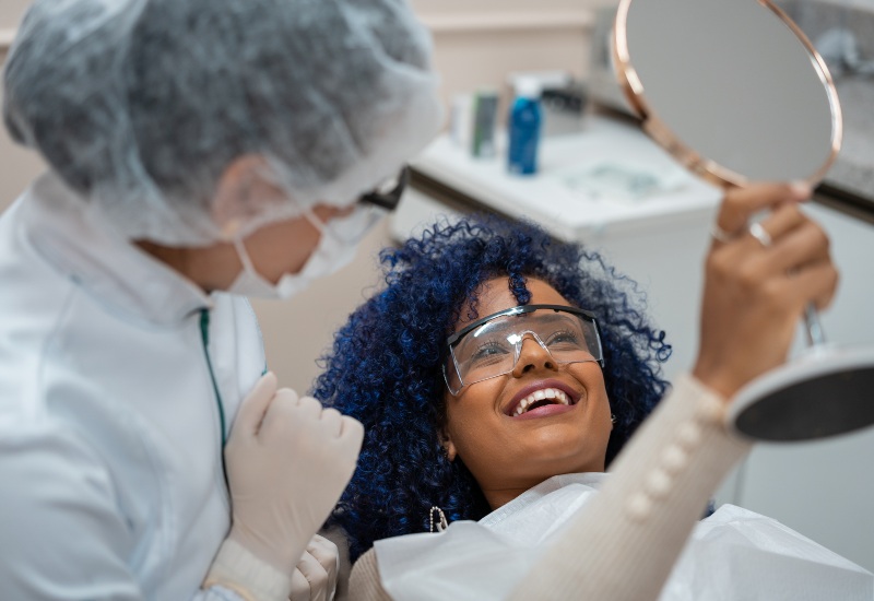 Woman admiring her smile after cosmetic dental procedure in Grand Rapids, MI